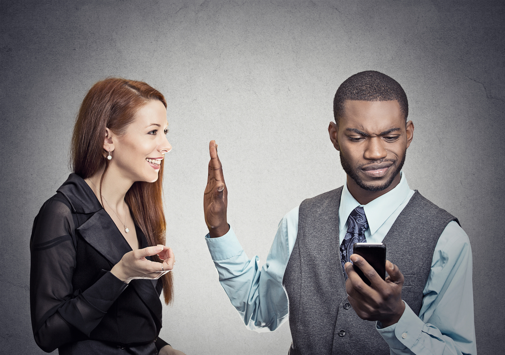 man looking at phone in his hand and ignoring woman