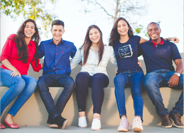 Group of people sitting next to each other on a stone wall