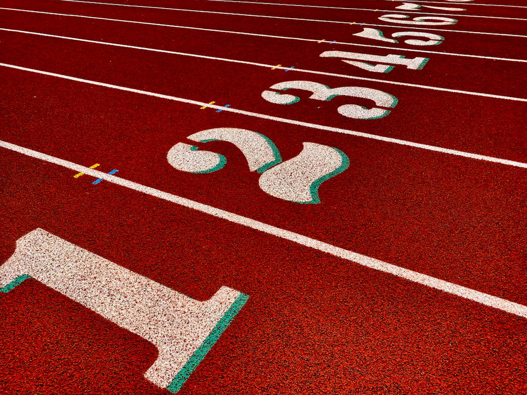 Red running track with white lane markers counting up from 1