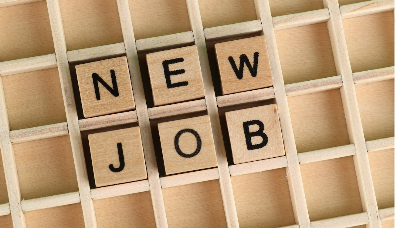 Wooden tiles that spell out NEW JOB laid in a wooden box frame
