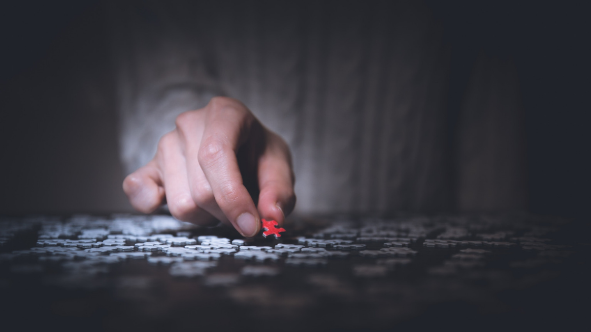 Man's hand assembling a puzzle