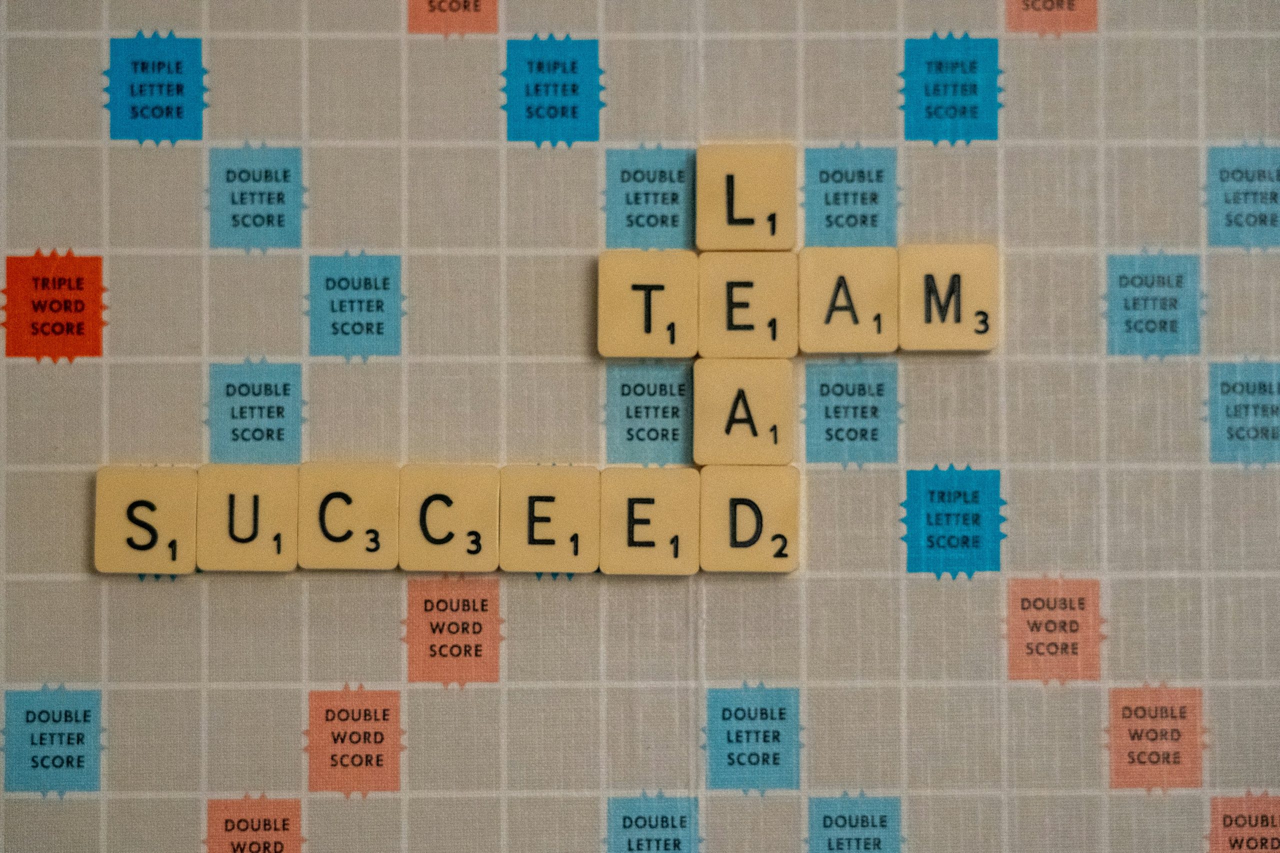 Scrabble board spelling out Lead, Team and Succeed